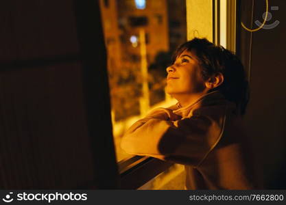 Girl looking out her bedroom window at night to see the moon and stars.. Girl looking out window at night to see the moon and stars.