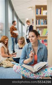 Girl looking outside with group of students discussing in library