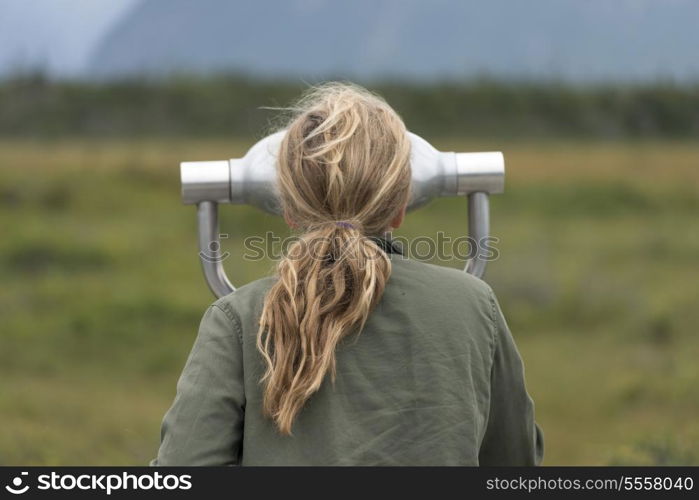 Girl looking through a coin-operated binoculars, Western Brook Pond, Norris Point, Gros Morne National Park, Newfoundland And Labrador, Canada