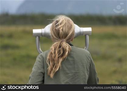 Girl looking through a coin-operated binoculars, Western Brook Pond, Norris Point, Gros Morne National Park, Newfoundland And Labrador, Canada