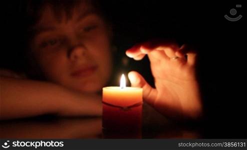 girl looks at burning candle.