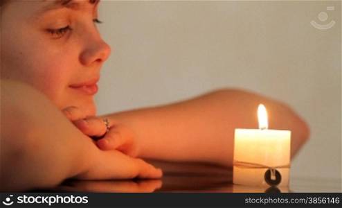 girl looks at burning candle.