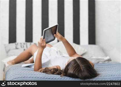 girl lying bed using digital tablet