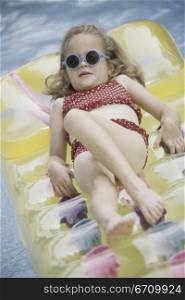 Girl lying on an inflatable raft in a swimming pool