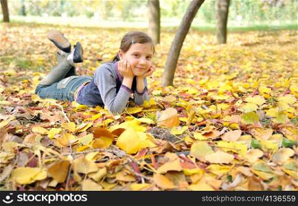 girl lying on fall leaves outdoors