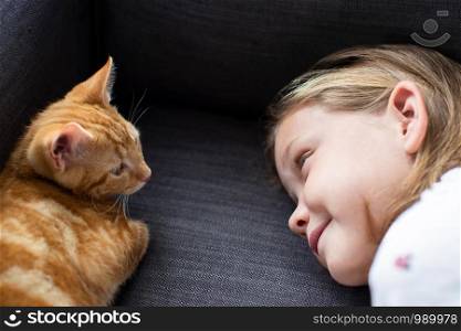Girl Lying On Sofa At Home Looking Lovingly At Pet Cat
