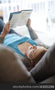 Girl lying on sofa reading a book