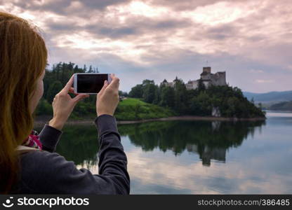 girl making a photo shoot of castle niedzica with the Smartphone, Poland