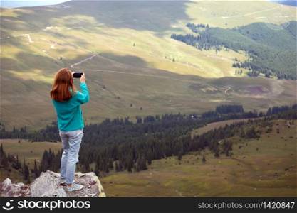 girl making a photo shoot of mountains with the smartphone