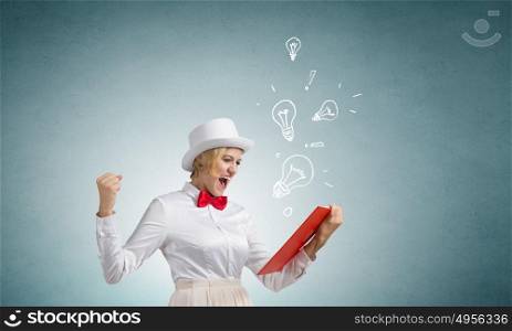 Girl mastering science. Young emotional woman in white cylinder with book in hand