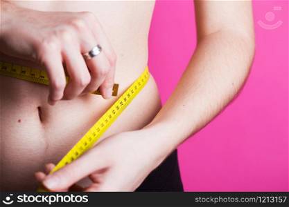 girl measures her volumes with a centimeter on a pink background. healthy and beautiful body. Female body, slim waist.