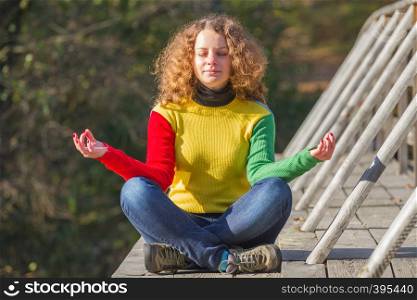 Girl meditates on the bridge in autumn
