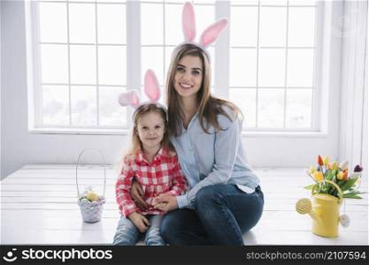 girl mother bunny ears sitting near basket with colored eggs