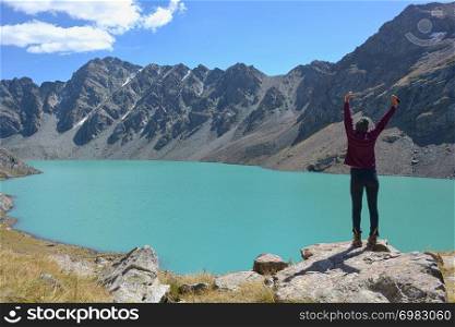 Girl near beautiful mountain lake. Ala-Kul lake in Terskey Alatoo mountains, Tian-Shan, Karakol, Kyrgyzstan