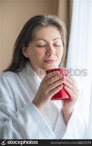 Girl near the window enjoying the aroma of coffee