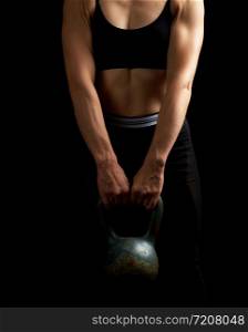 girl of athletic appearance holds an iron kettlebell in front of her, strength sports, low key