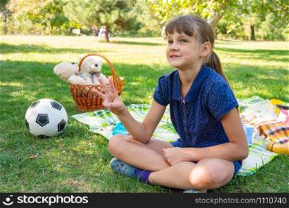 Girl on a picnic counts goals scored on fingers