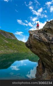 Girl on a rock above an alpine lake