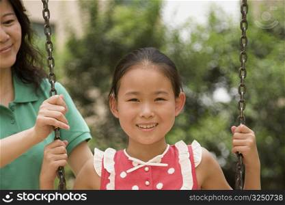 Girl on a swing with her mother behind her