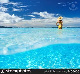 Girl on a tropical beach with white sand bottom underwater and above water split view