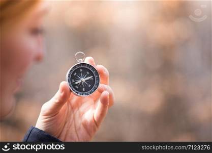 Girl on an adventure is holding a compass in her hand for finding is route, blurry face