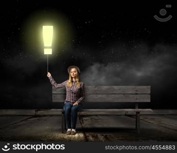 Girl on bench. Young woman in casual holding balloon shaped like exclamation mark