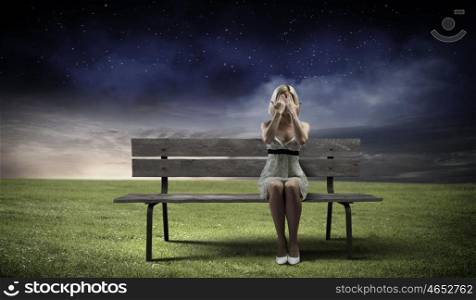 Girl on bench. Young woman sitting on bench closing eyes with palms