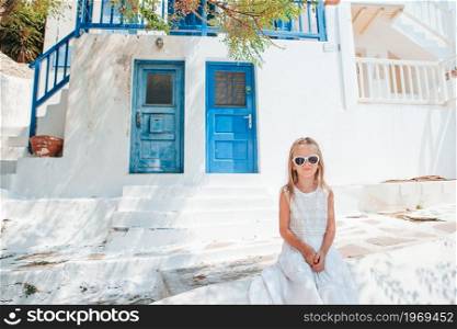 Girl on Mykonos vacation outdoors. Adorable little girl at old street of typical greek traditional village
