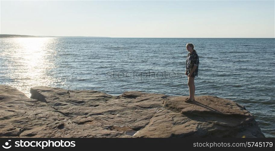 Girl on rocky coastline at Atlantic Ocean, Cavendish Beach, Green Gables, Prince Edward Island, Canada
