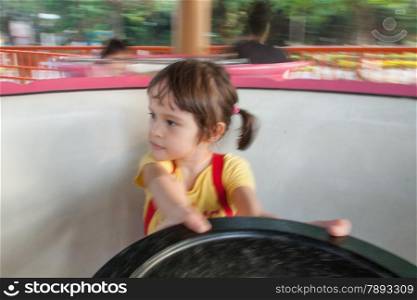 Girl on spinning teacup at amisement park