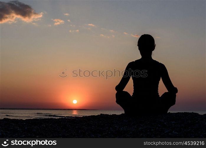 girl on the beach at dawn in yoga assana, silhouette