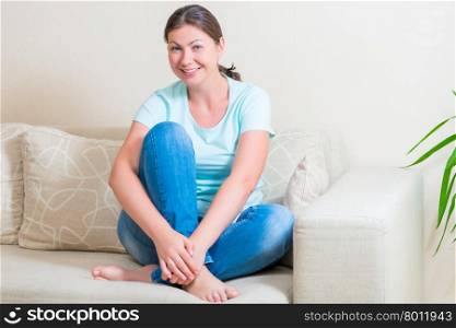 Girl on the bed barefoot sitting and smiling