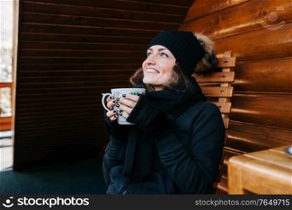 girl on the porch of a snow-covered wooden house in the winter mountains