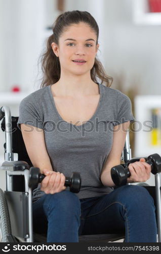 girl on the wheelchair holding weights