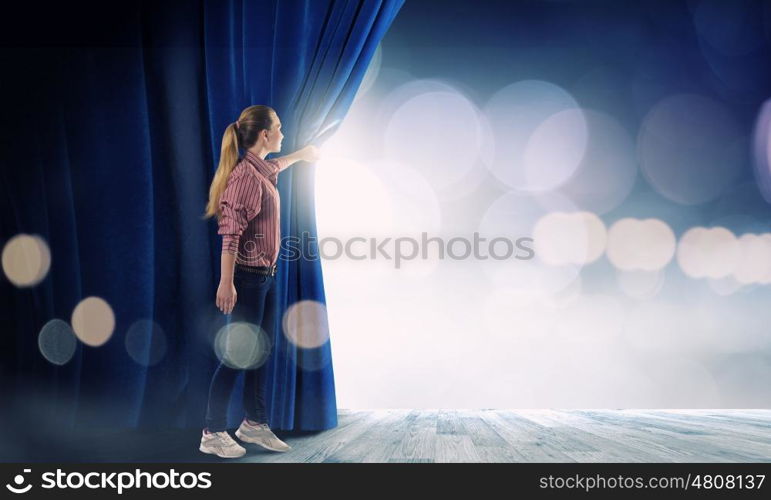 Girl opening curtain. Young woman in casual opening stage curtain