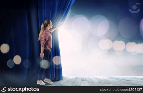 Girl opening curtain. Young woman in casual opening stage curtain