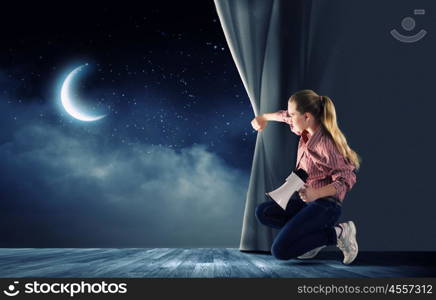 Girl opening curtain. Young woman in casual with megaphone opening curtain