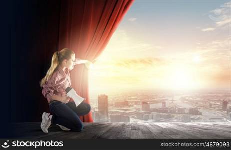 Girl opening curtain. Young woman in casual with megaphone opening curtain