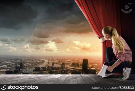 Girl opening curtain. Young woman in casual with megaphone opening curtain