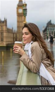 Girl or young woman drinking coffee in a disposable cup on Westminster Bridge with Big Ben and the Houses of Parliament in the background, London, England, Great Britain
