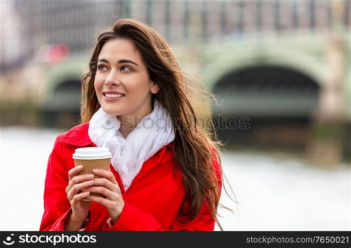 Girl or young woman in a modern city, drinking coffee by Westminster Bridge over the River Thames, London, England, Great Britain