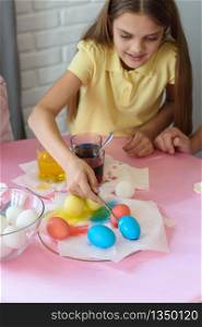 Girl paints Easter eggs in a special solution and puts on a plate