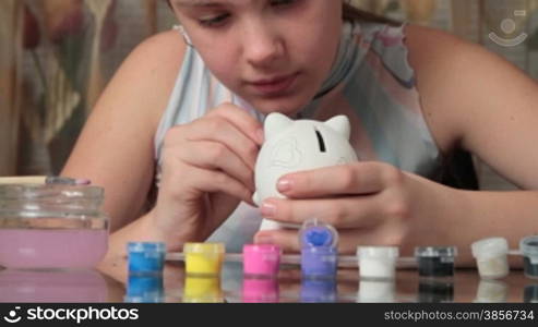 girl paints pig-coin box.