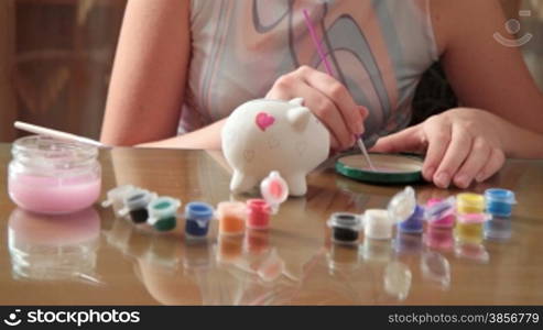 girl paints pig-coin box.