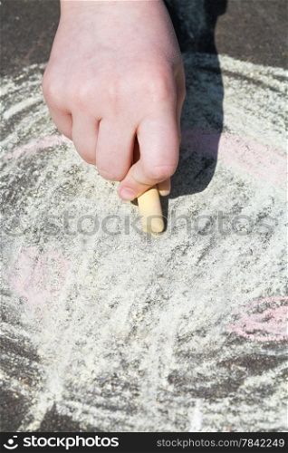 girl paints with colored chalk on asphalt outdoors close up
