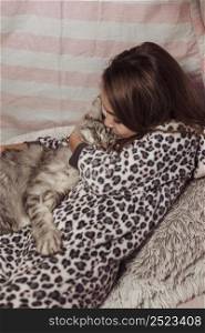 girl pajamas kissing her cat