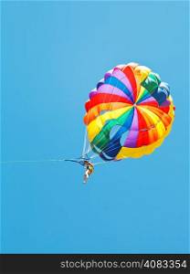girl parakiting on parachute in blue sky in summer day