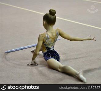 Girl performs mandatory exercises in rhythmic gymnastics
