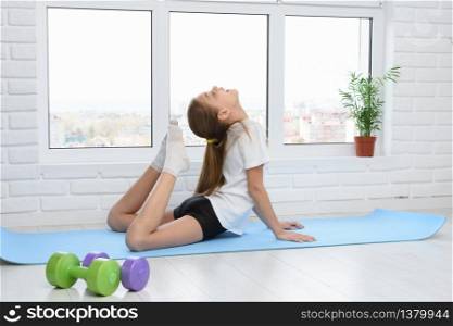 Girl performs stretching the muscles of the back while doing home