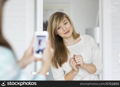 Girl photographing sister through smart phone at home